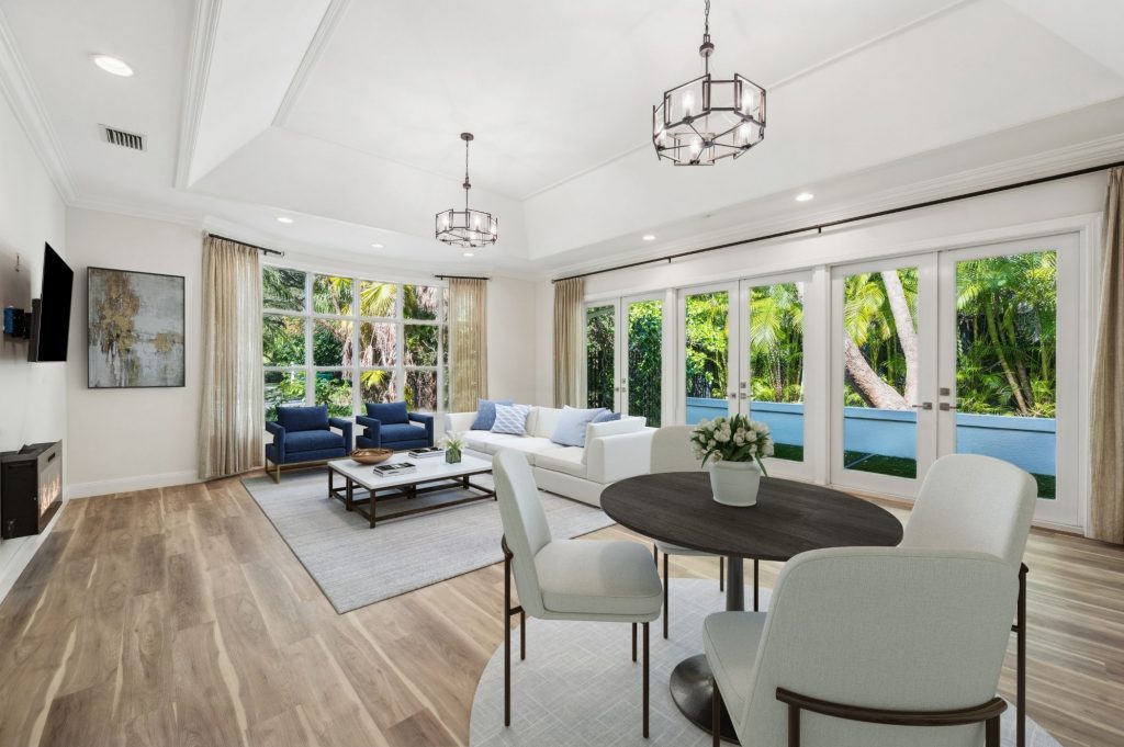Bright open-plan living and dining area with tray ceiling and floor-to-ceiling French doors