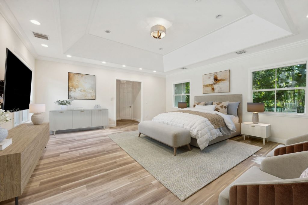 Expansive primary bedroom with tray ceiling, upholstered king bed and sitting area