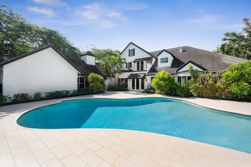 Rear exterior with large freeform swimming pool and travertine pool deck